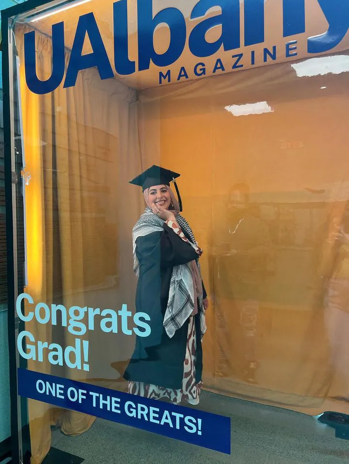 A graduate poses for a photo in the UAlbany Magazine photo booth.