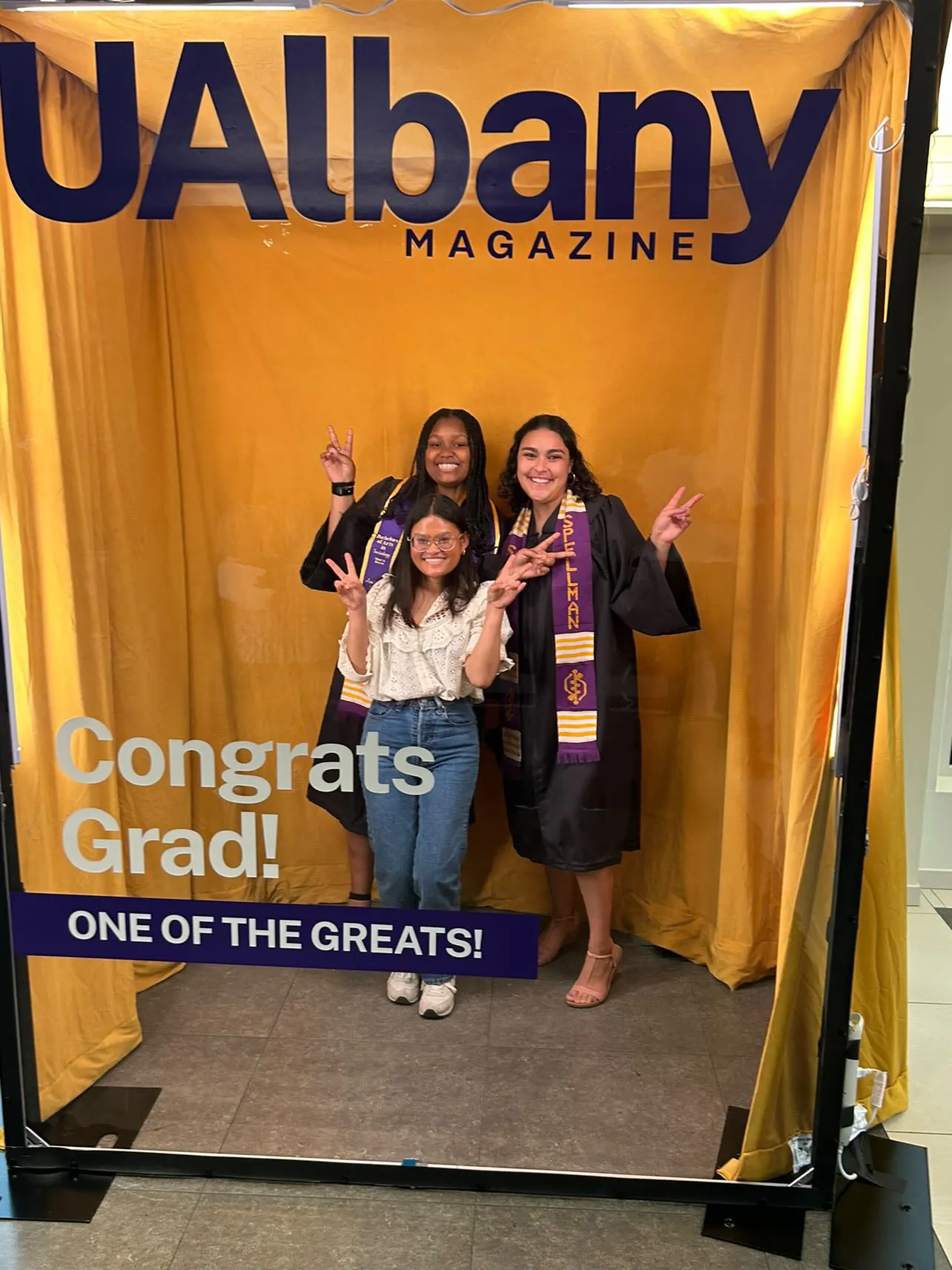 Two graduates and their friend pose for a photo while holding up hands in peace signs.