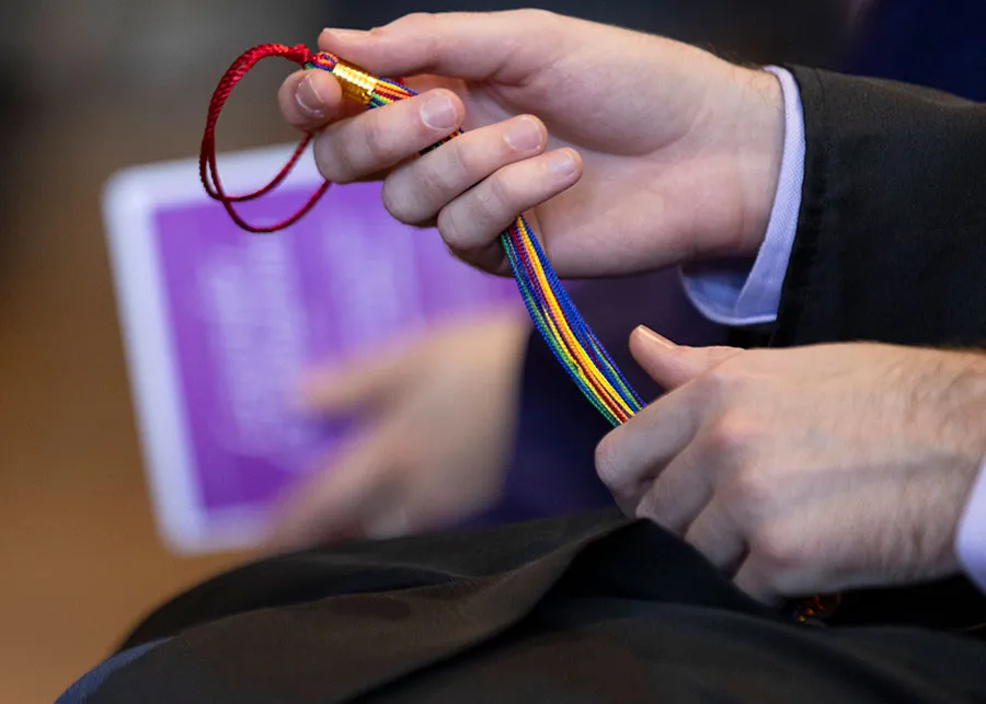 A close up of hands holding a rainbow cord.