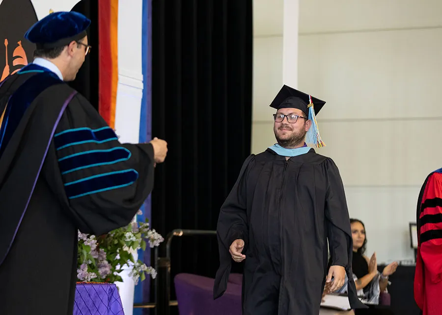 A graduate crossing the stage during the Lavender Ceremony.