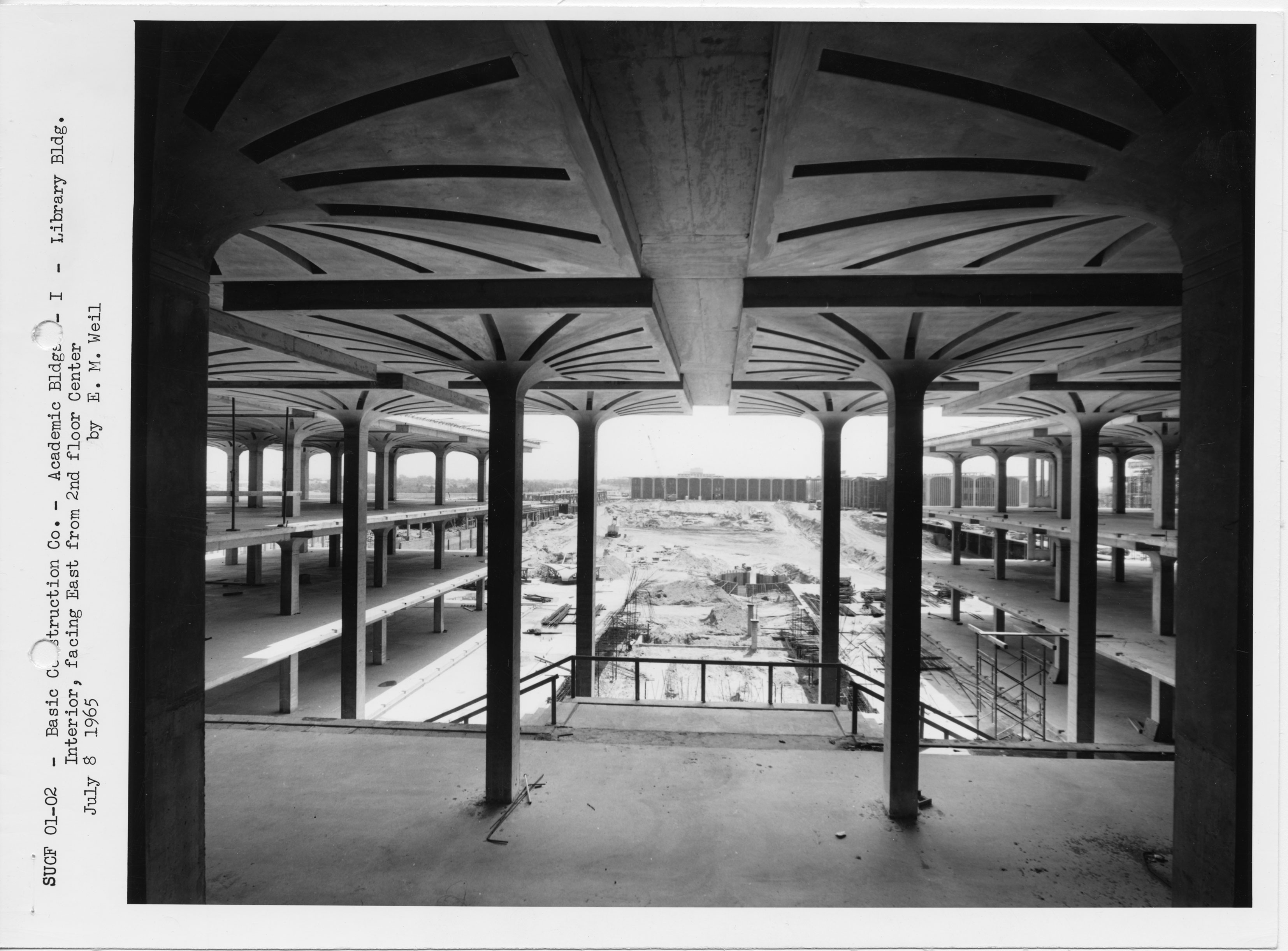 During construction in July 8, 1965. You can see the ring of the base of the water tower being formed in the middle of the photo. This view is from the second floor library interior looking out at the fountain area.