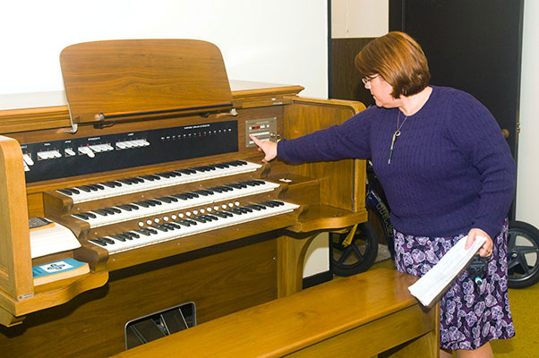 Photo of woman touching knobs on the carillon organ keyboard.