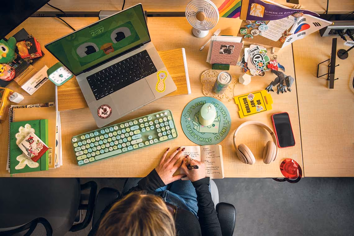 An overhead view of Adele at her desk writing in a journal.
