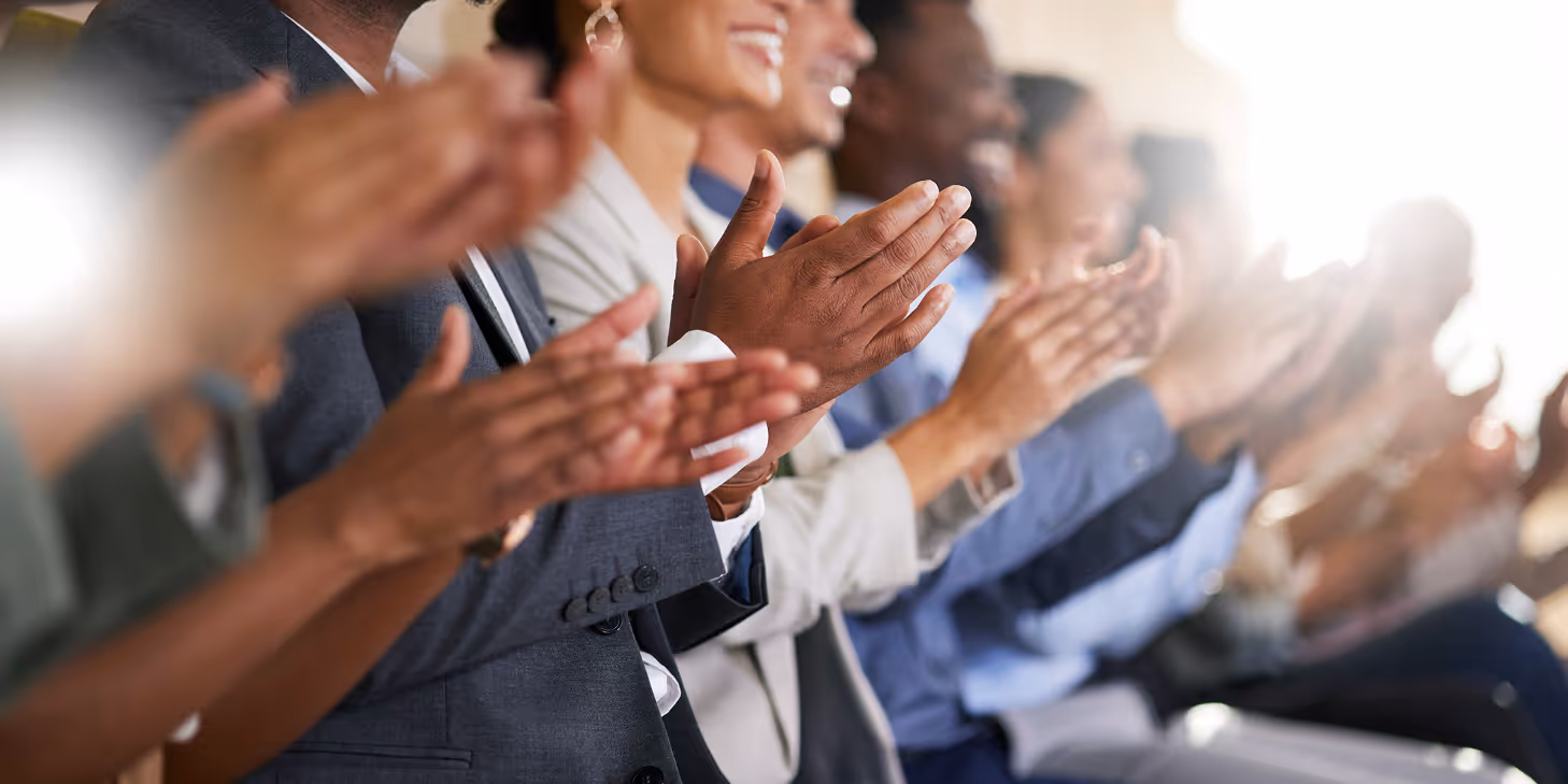 Audience clapping at a professional event, showing appreciation and support during a business or community recognition ceremony