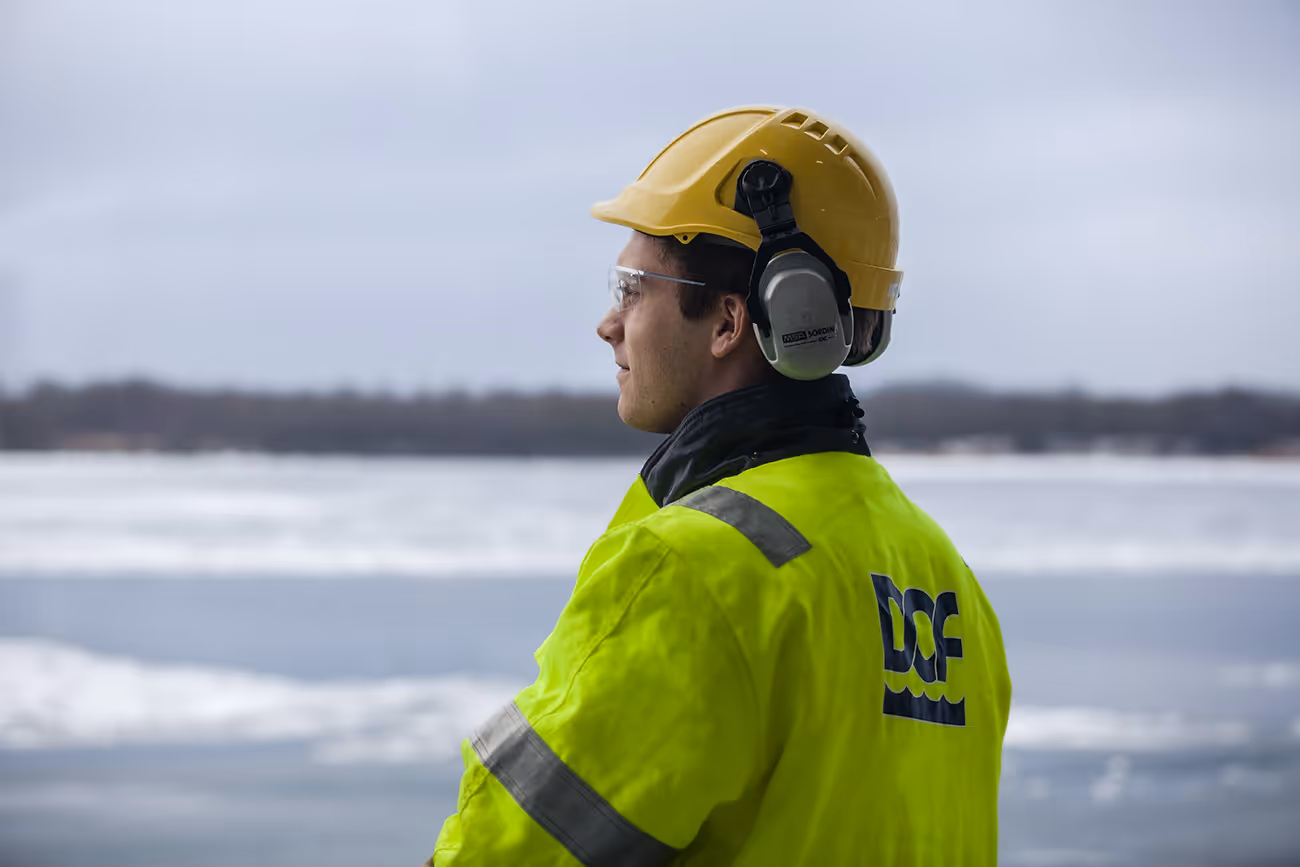A DOF worker with safety equipment is looking into the distance.