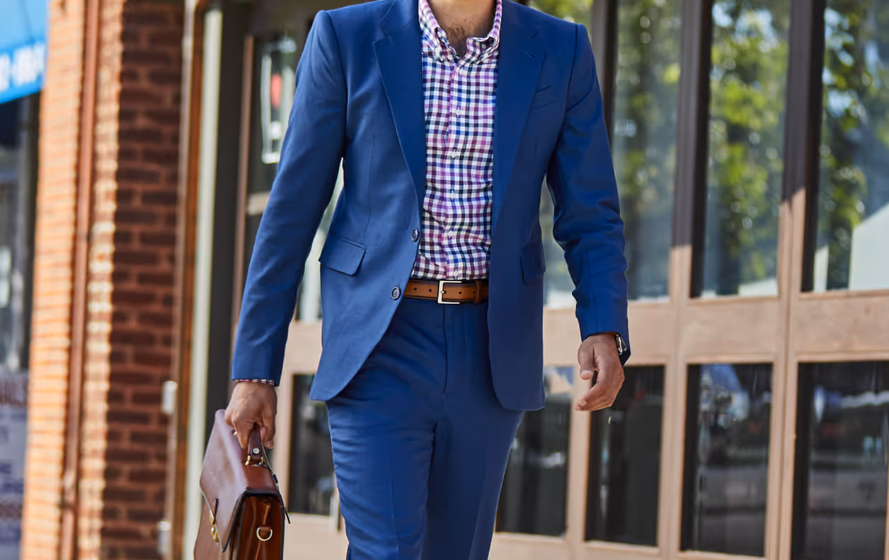 A man in a blue suit walking down the street.