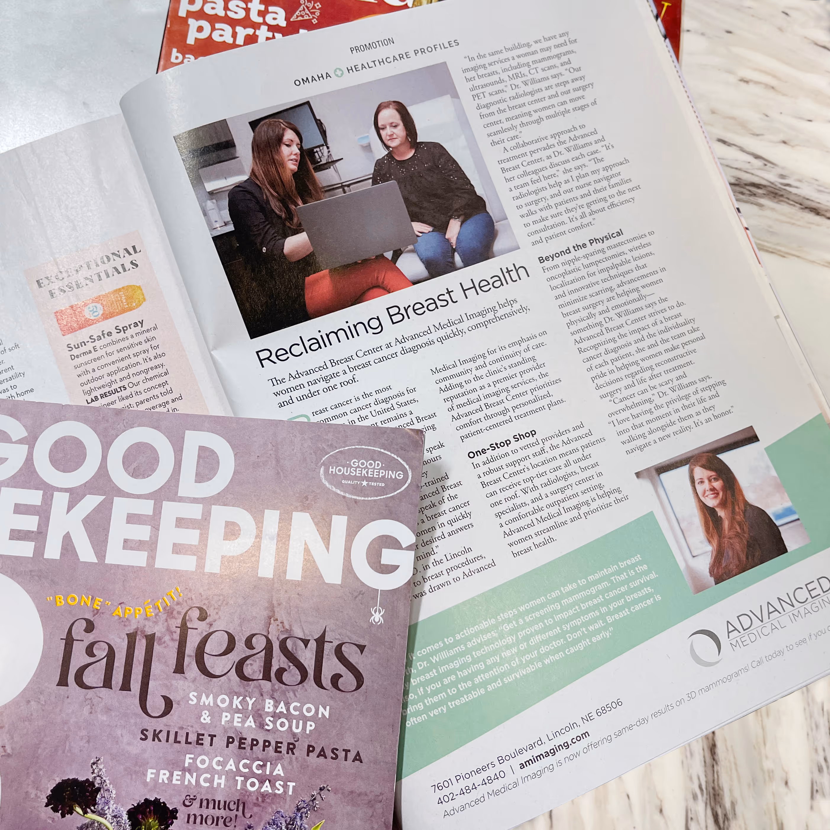 Open Good Housekeeping magazine showing an article titled 'Reclaiming Breast Health' with two women looking at a laptop and a portrait of a smiling woman.