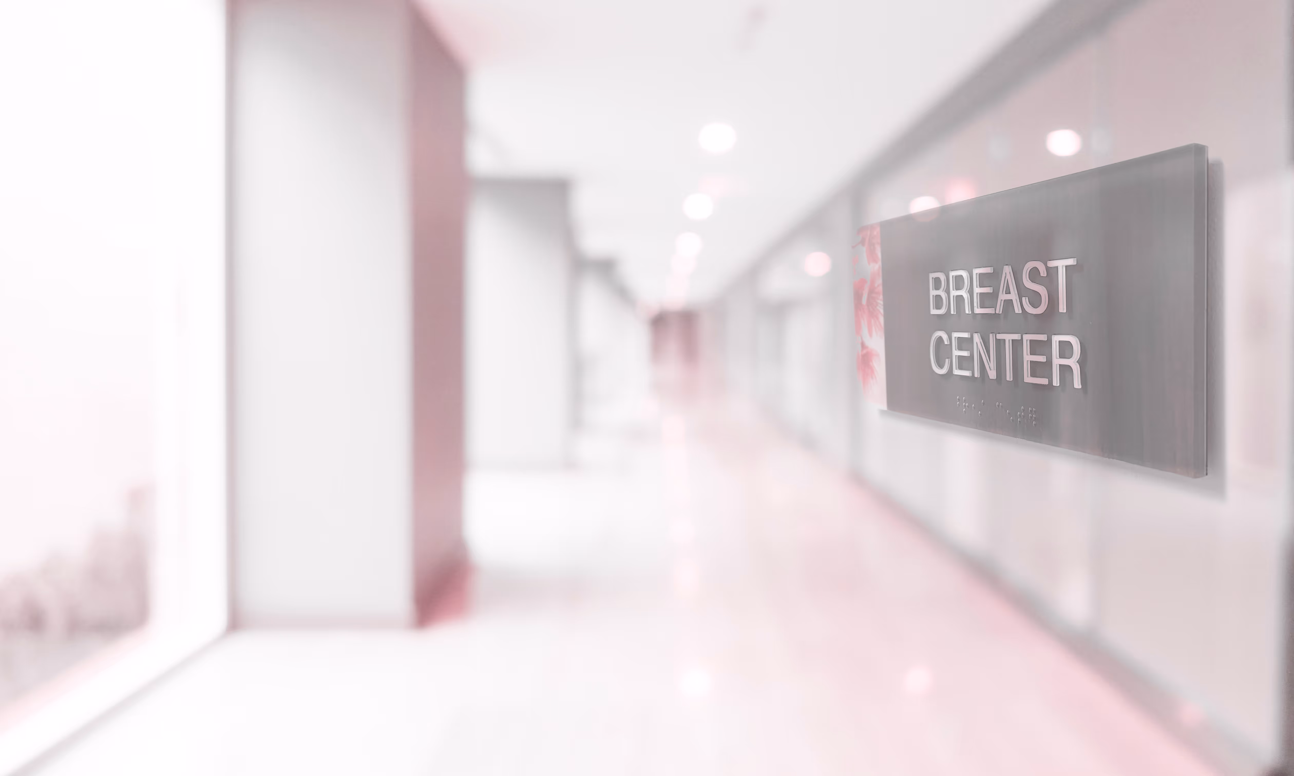 Sign reading 'Breast Center' mounted on a wall in a bright, modern hospital hallway.
