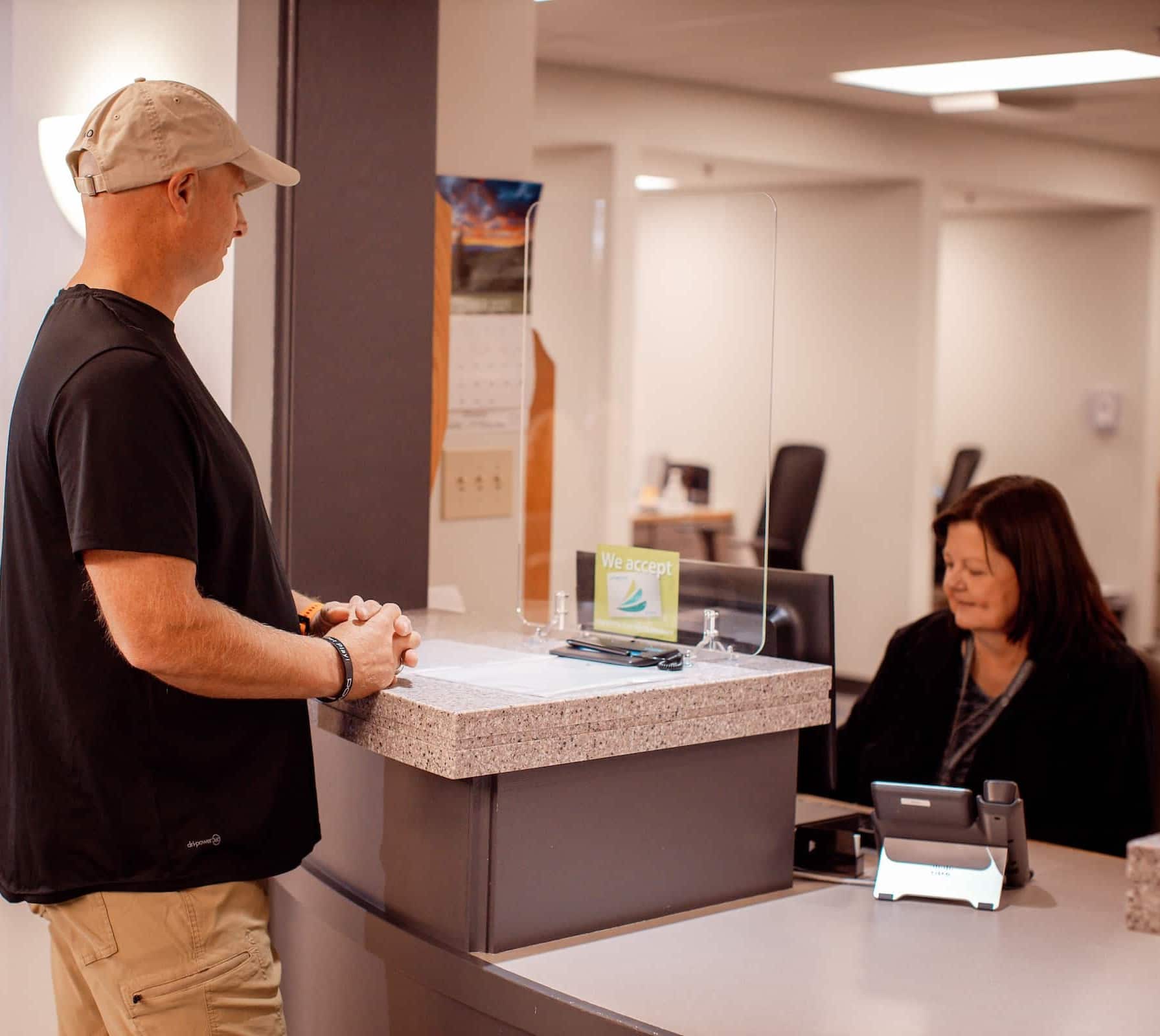 A patient checking in at the Advanced Medical Imaging front desk with a staff member behind the counter.