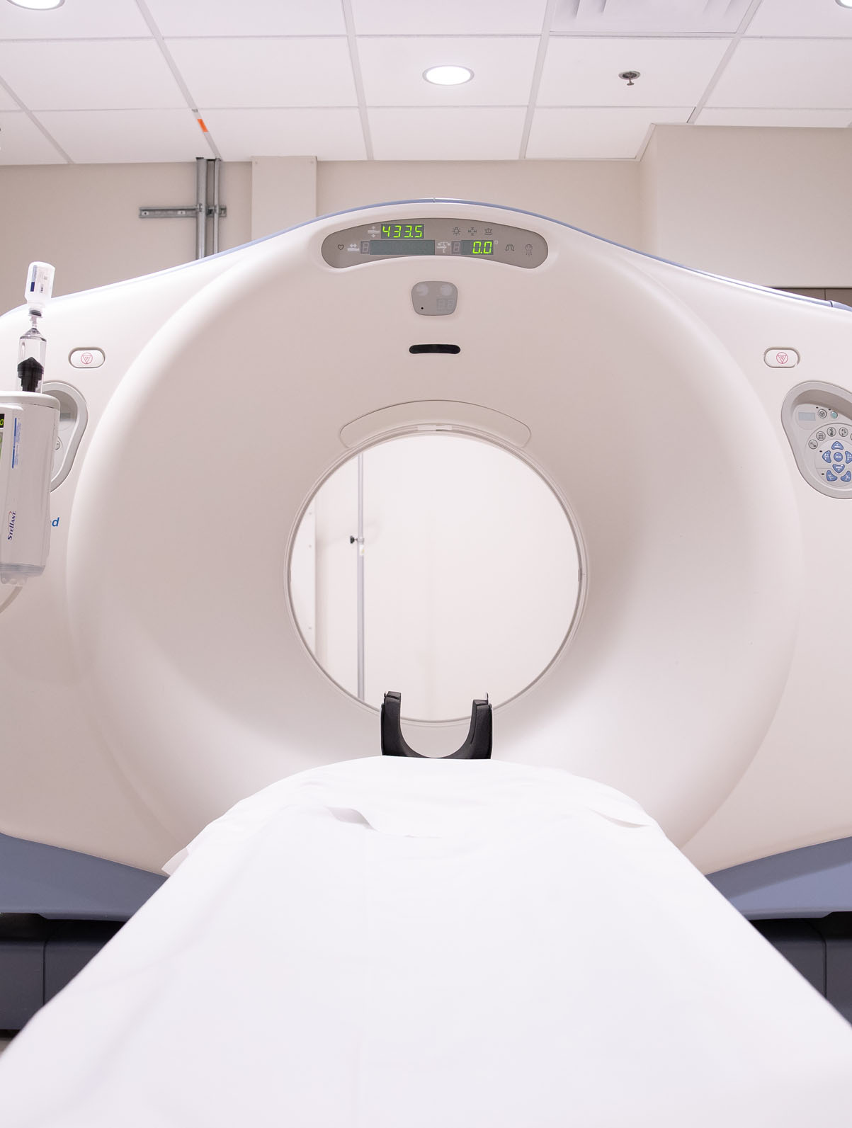 A CT scanner with an empty patient table positioned at the opening of the gantry.