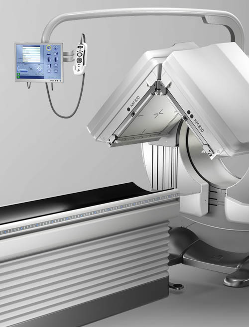 Nuclear medicine camera system with dual detection heads positioned above a patient exam table.