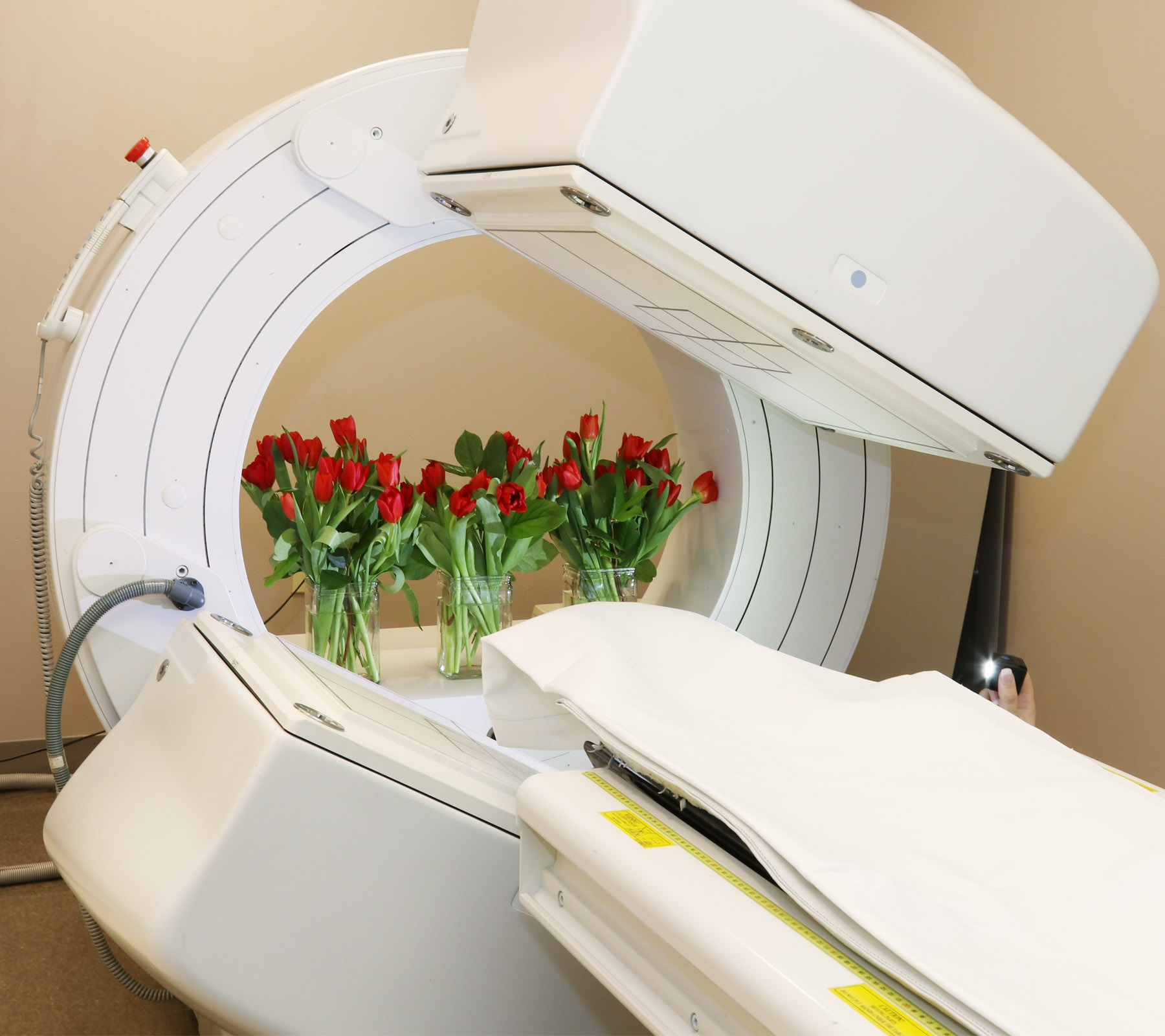 Vases of red tulips arranged inside a nuclear medicine scanner, marking Parkinsons Awareness Month.