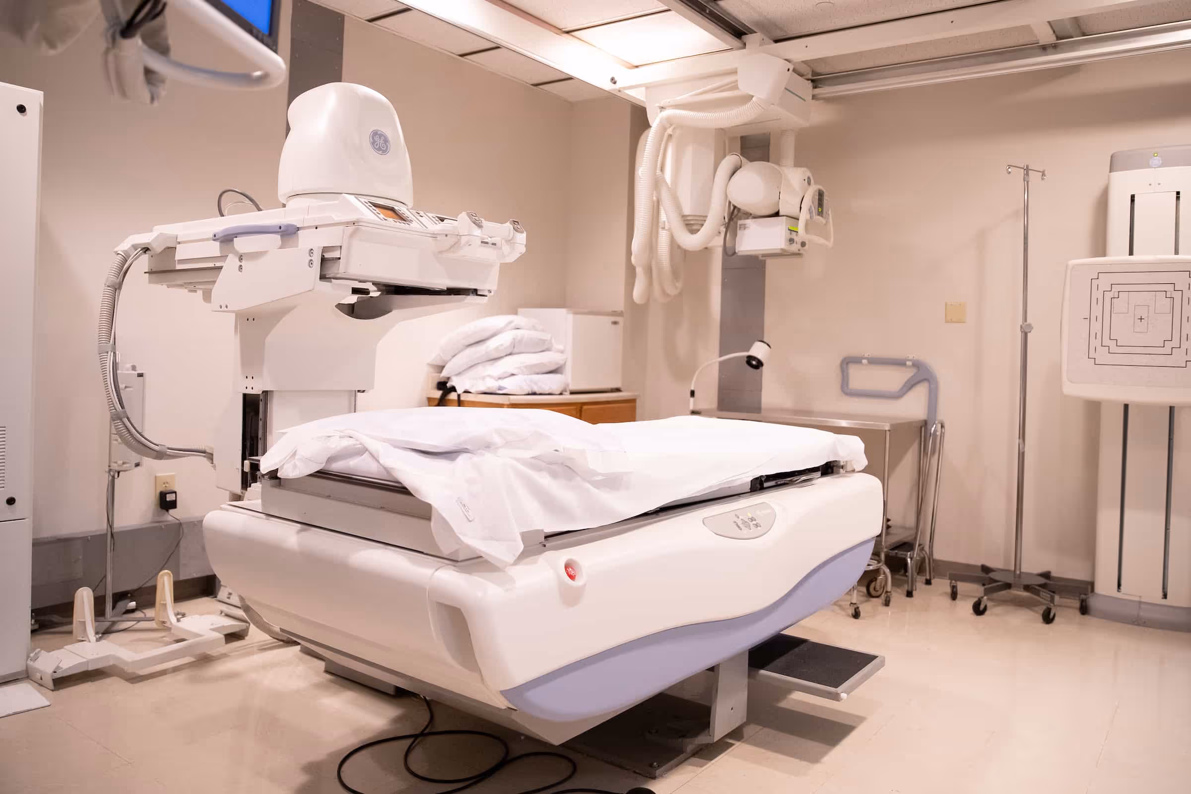 An interventional radiology suite with a procedure table beneath a ceiling-mounted imaging arm.