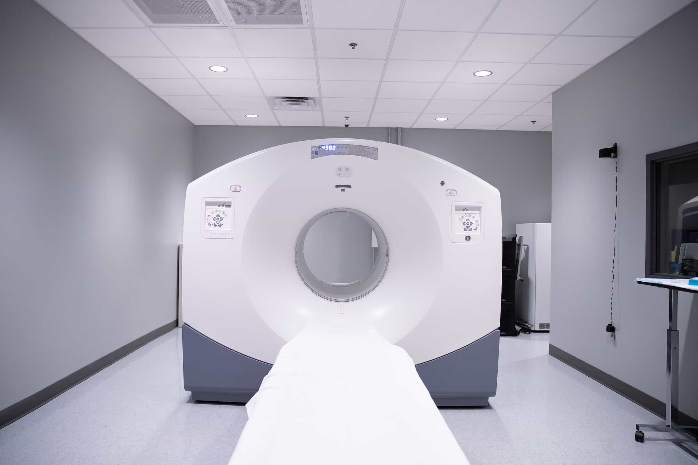 A CT scanner viewed head on, with the patient table extended toward the camera.
