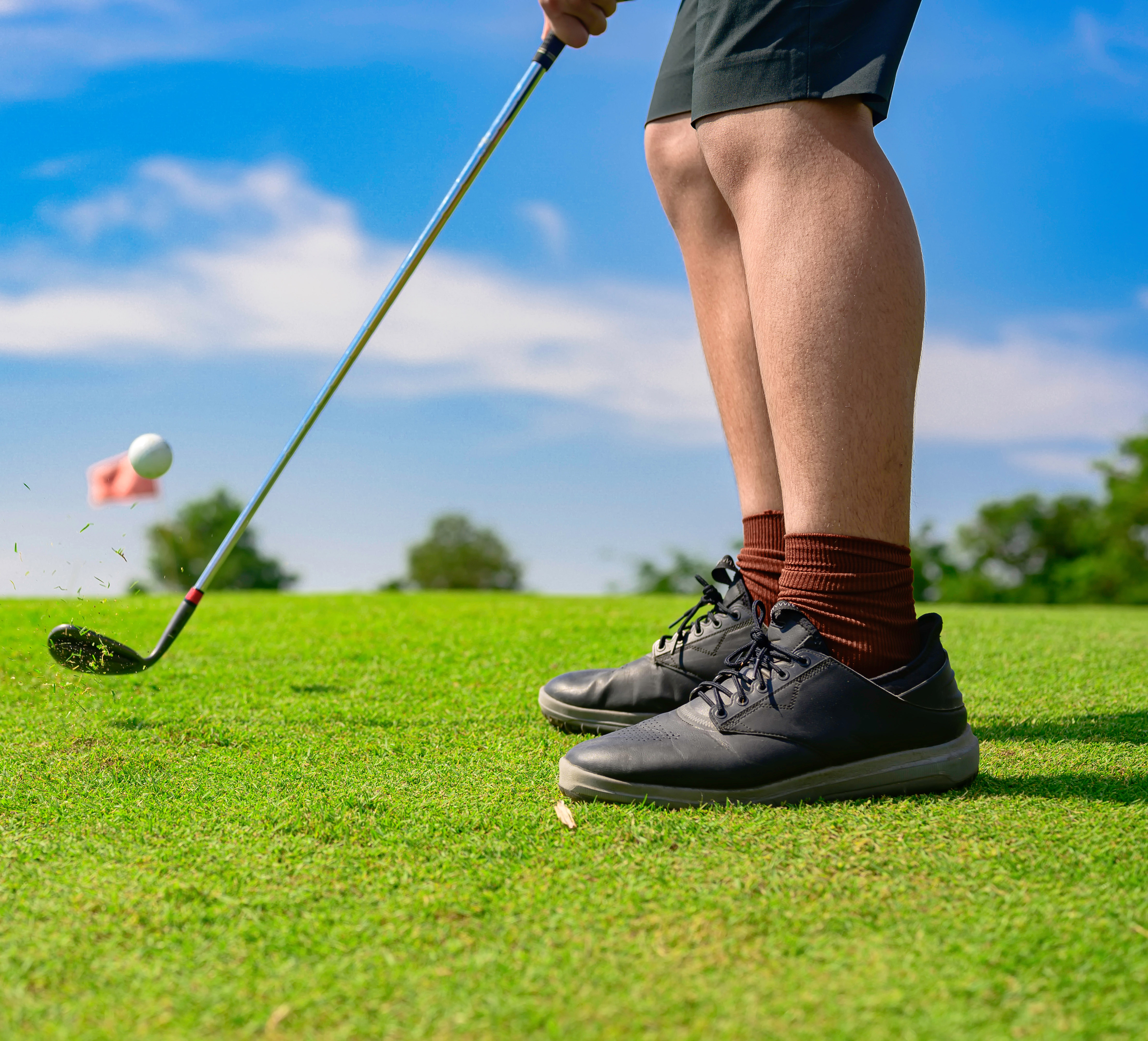 A golfer's legs on the green mid-swing on a sunny day.