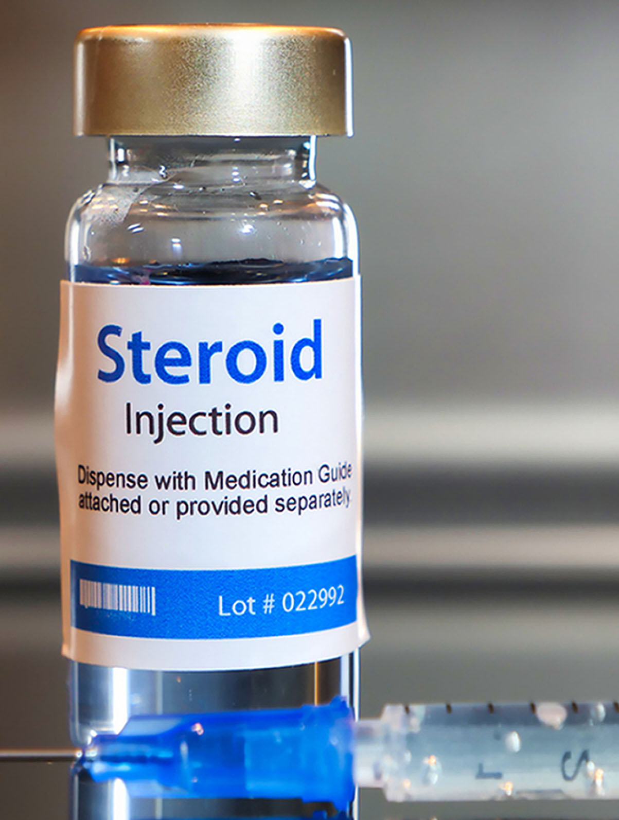 A vial labeled Steroid Injection standing on a metal surface.