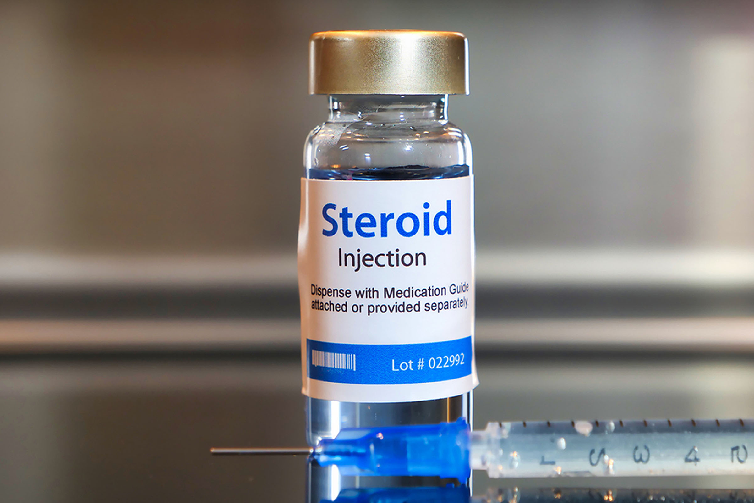 A vial labeled Steroid Injection beside a prepared syringe.