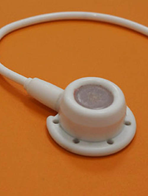 An implantable port with attached catheter on an orange background.