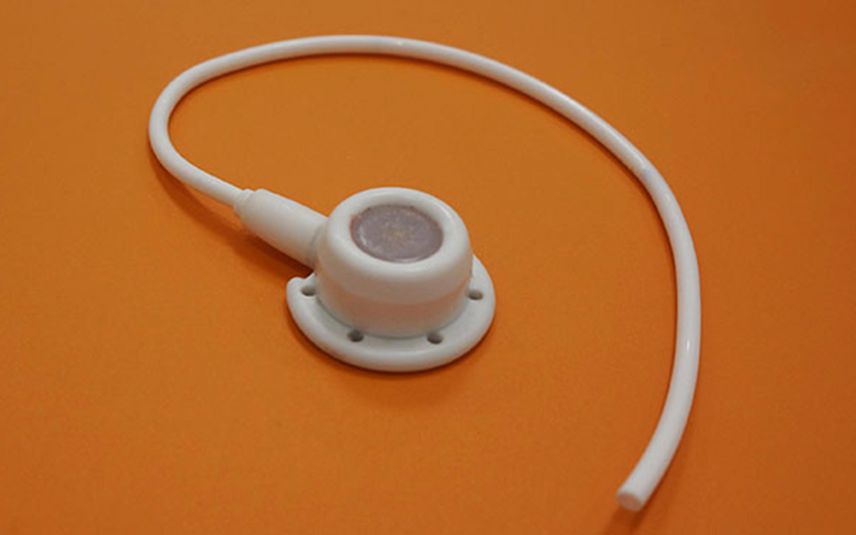 An implantable port and catheter coiled on an orange background.