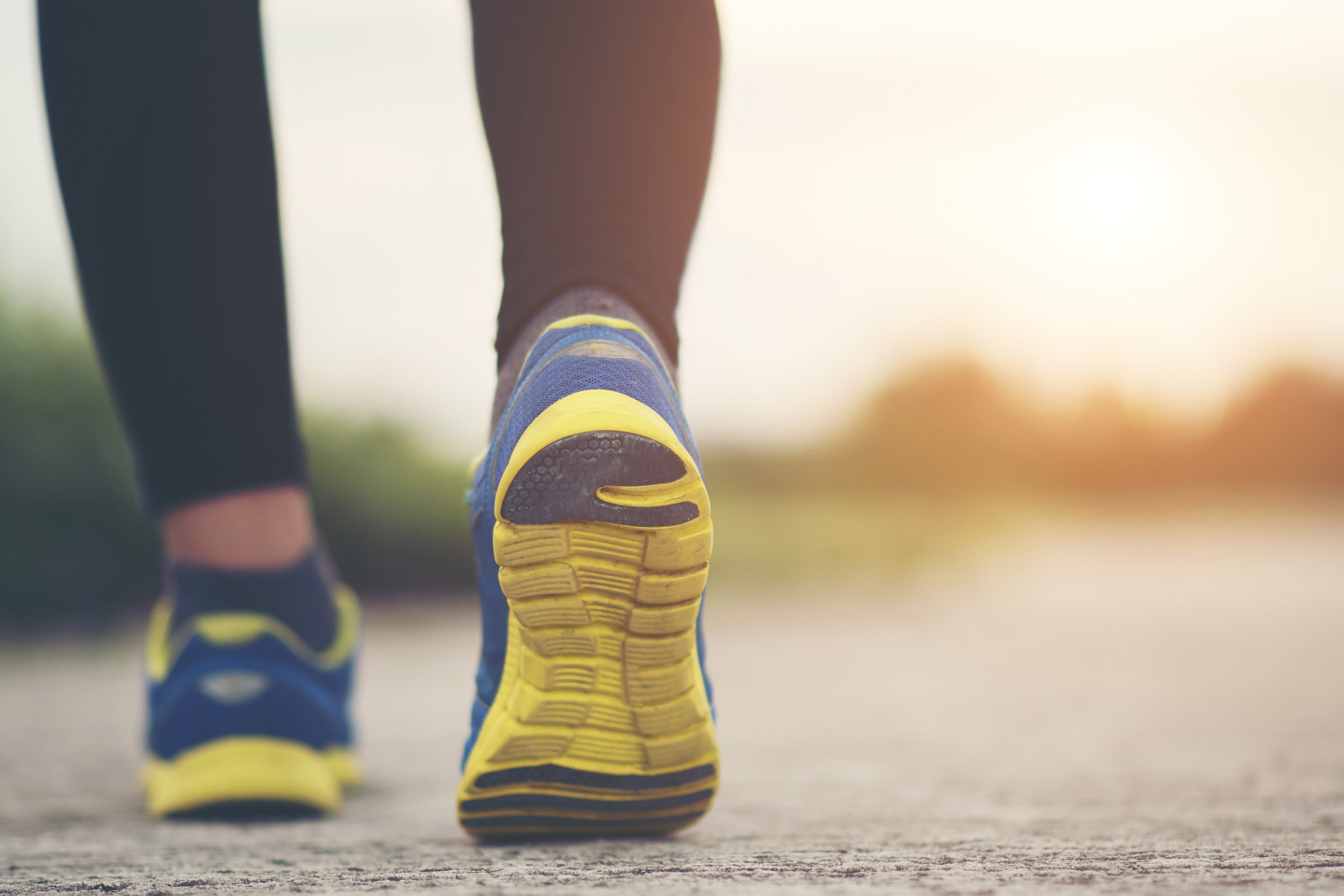 Close-up of running shoes walking along a paved path.