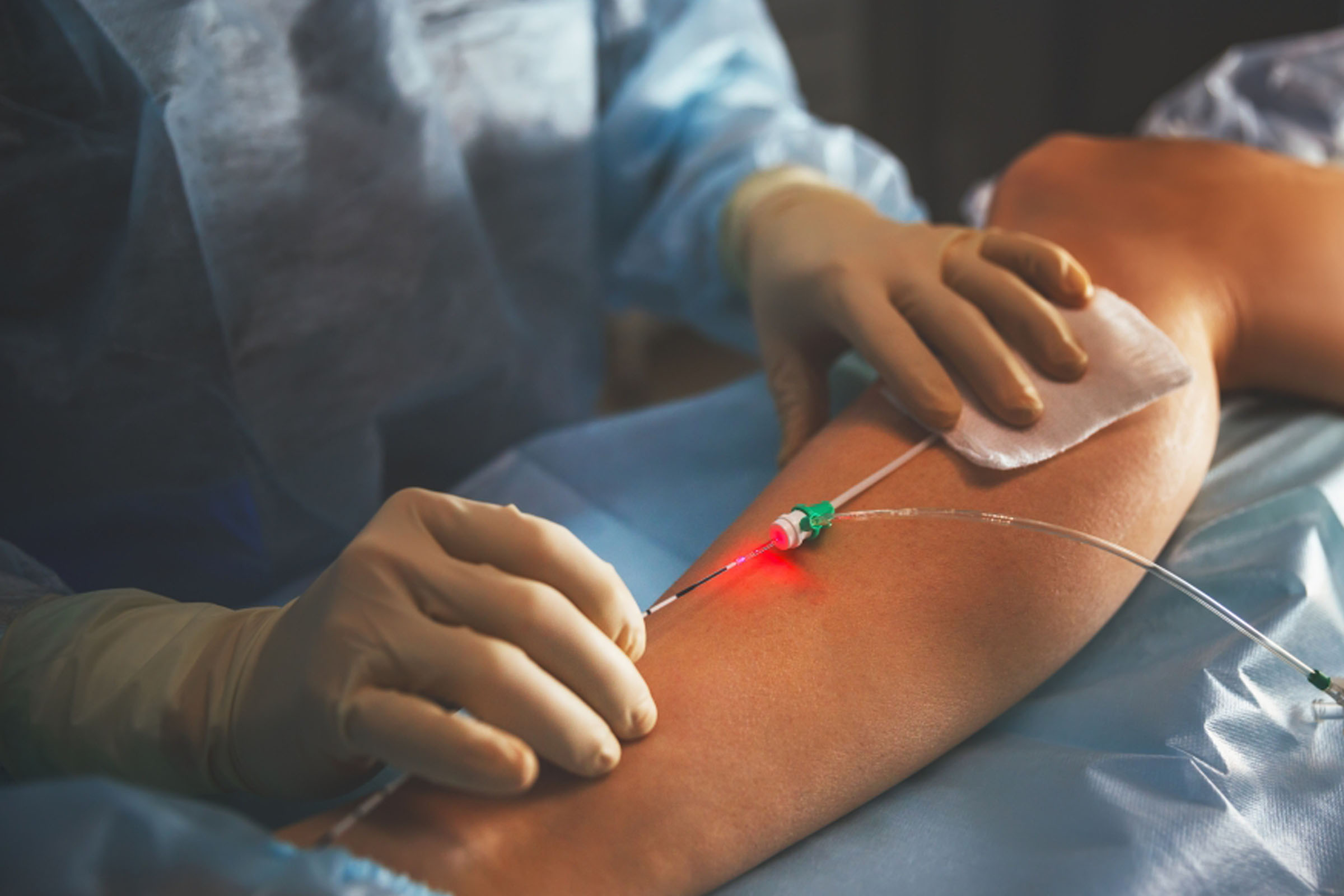 A clinician treating a patient's leg with a handheld laser device.