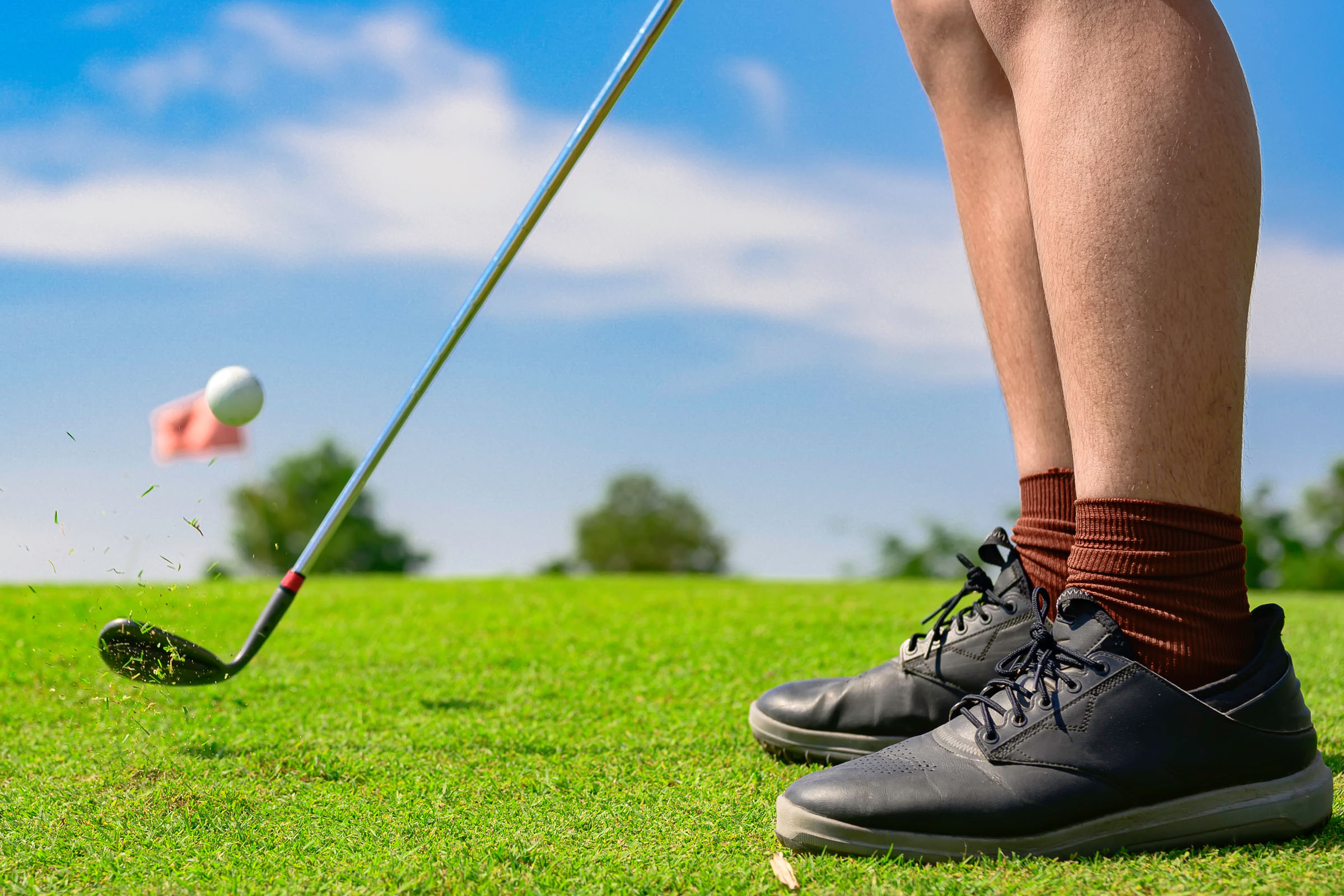 A golfer's legs on the green mid-swing on a sunny day.