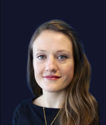Portrait of a woman with light skin, long brown hair, wearing a black top and neutral makeup, against a dark background.