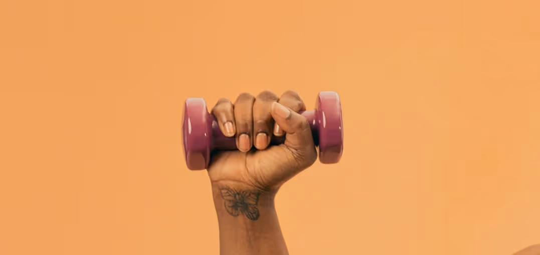 Hand with butterfly tattoo gripping a purple dumbbell against an orange background.
