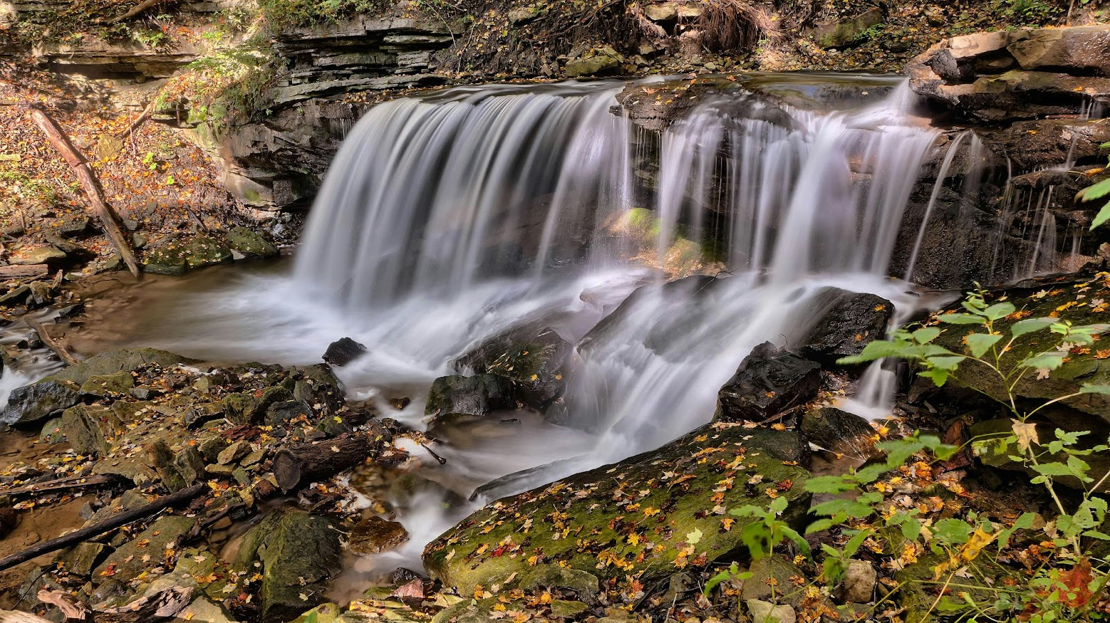 A tranquil waterfall surrounded by autumn leaves and rocks at a scenic nature spot near Toronto.