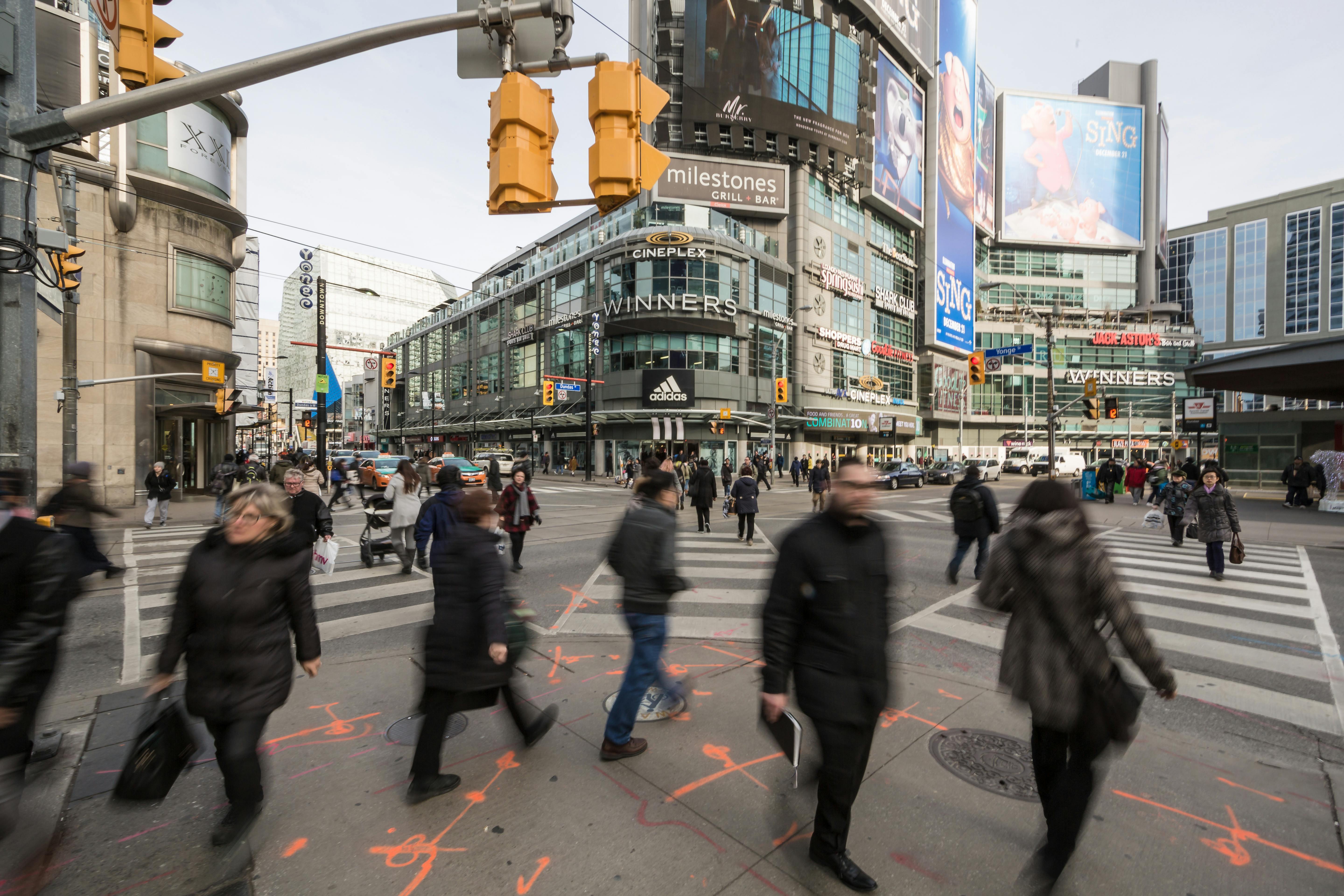 Many people crossing the street at the Yonge and Dundas busy intersection in Toronto.