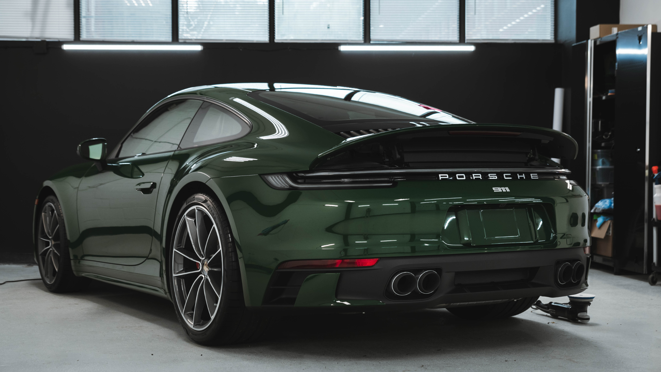 Green Porsche 911 parked indoors after professional exterior detailing, showing glossy paint finish and clean body lines.