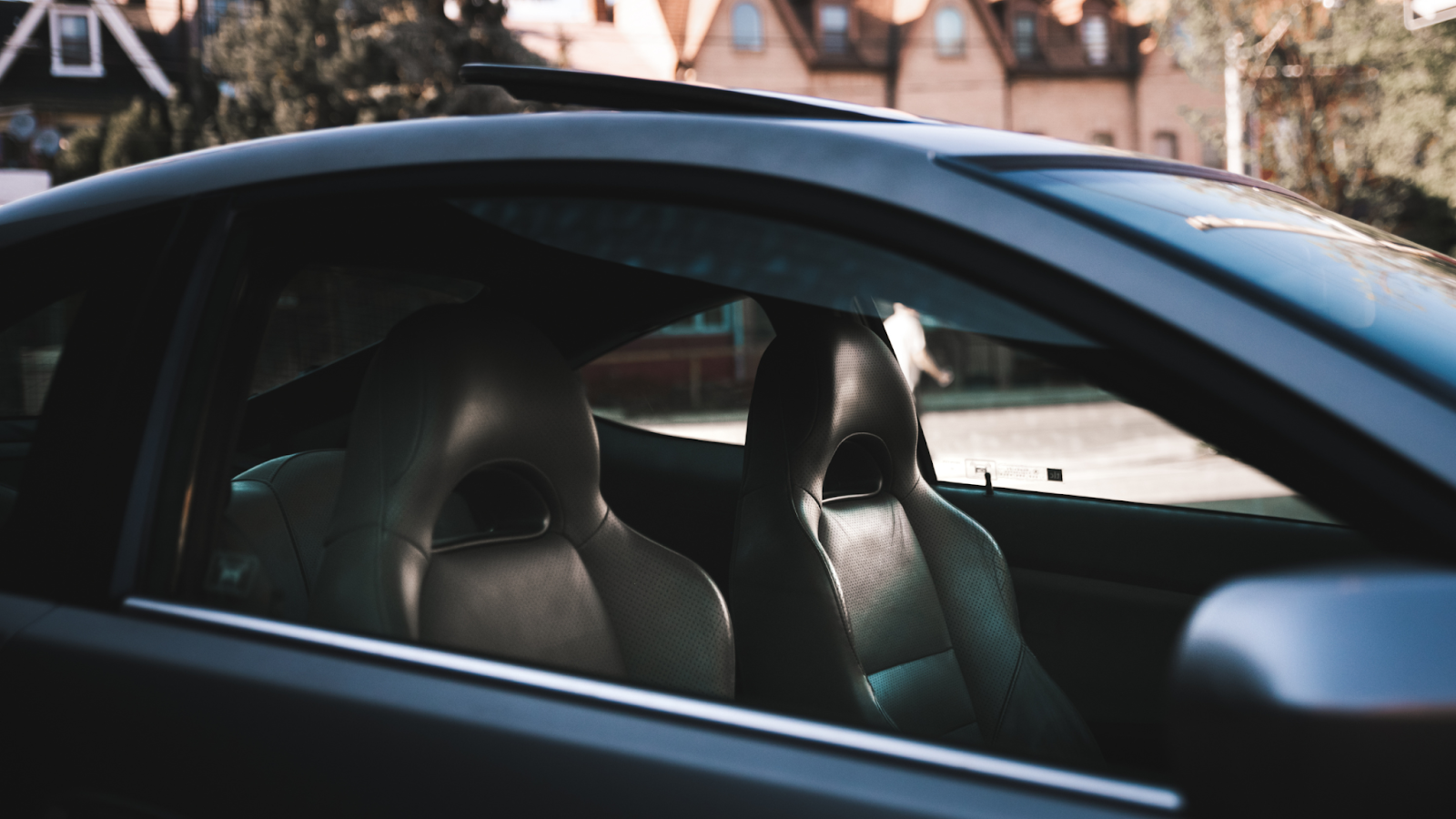 Clean car interior seats viewed through the side window after professional interior detailing, showcasing a well maintained and comfortable driving space.