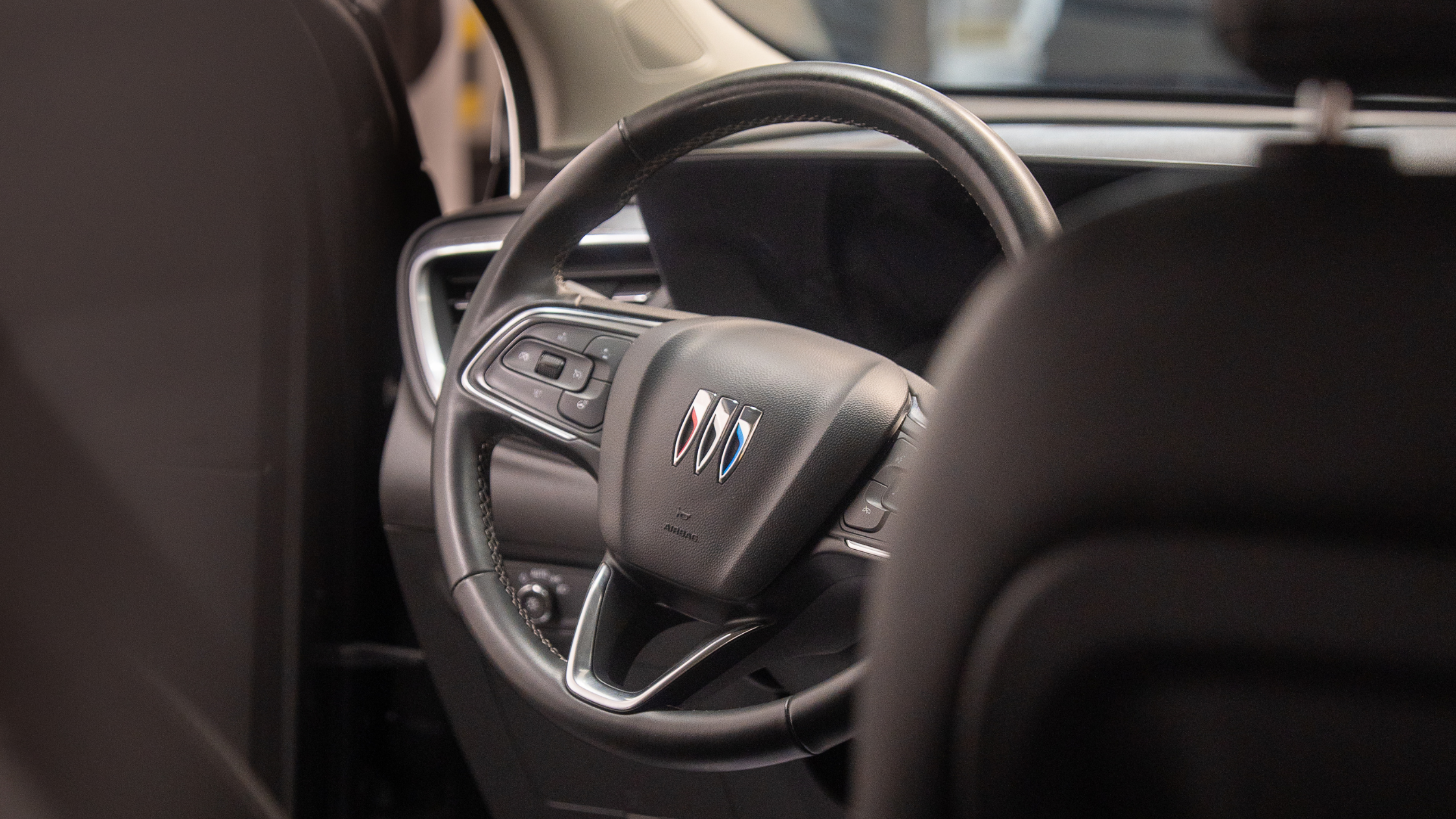 Interior view of a vehicle steering wheel with control buttons and a centered emblem, highlighting a clean dashboard and modern design. Everything cleaned by ALPHASHINE.