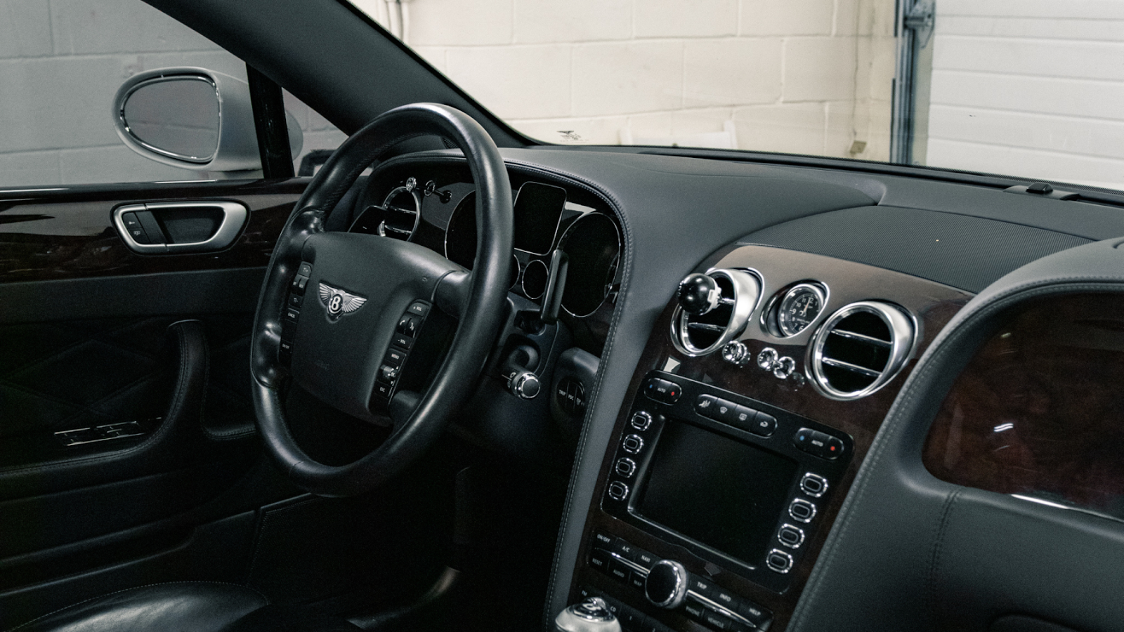 Luxury car interior after professional detailing showing polished dashboard, leather seats, and spotless steering wheel.