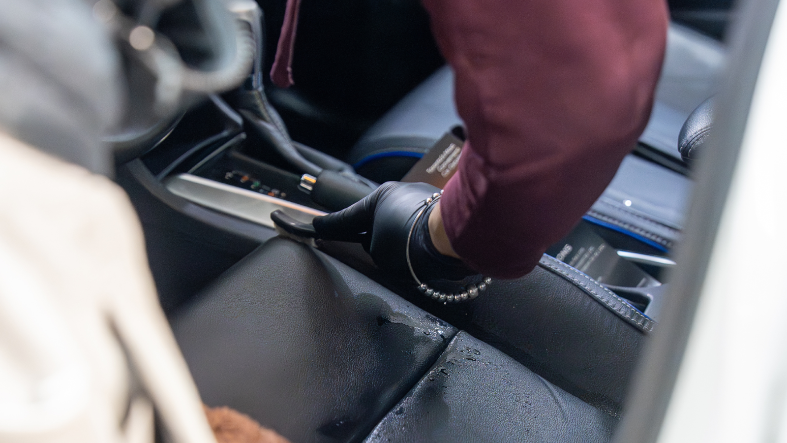 Professional car detailing technician cleaning vehicle interior console with microfiber tool during deep interior car detailing service.