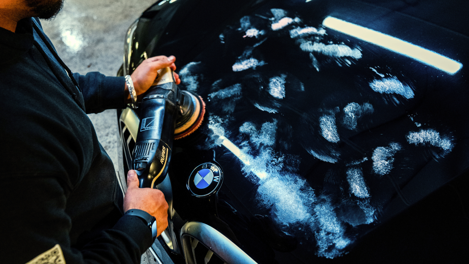 Professional paint correction in Toronto with technician machine polishing BMW hood to remove scratches and restore gloss.