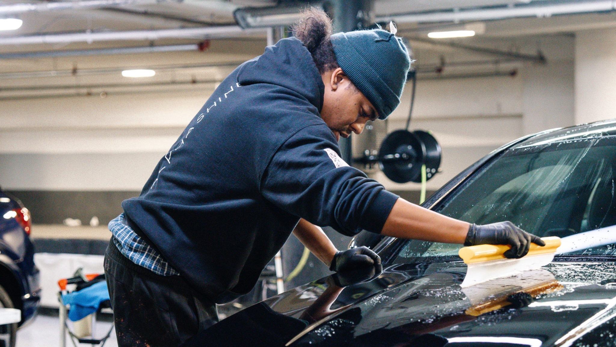 Technician using squeegee to remove water during car drying at ALPHASHINE, exterior detailing service in Toronto