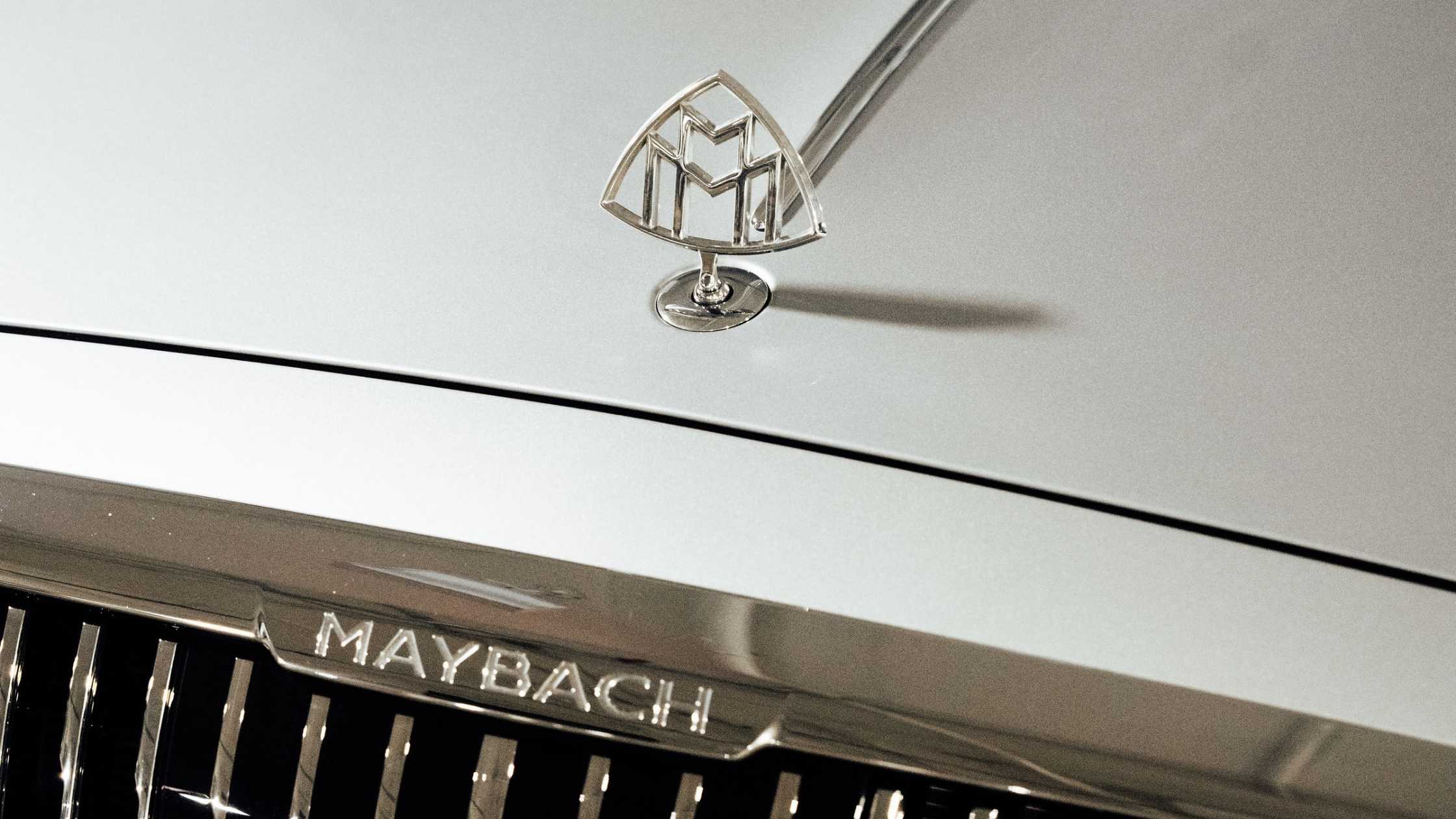 Close up of a Maybach hood ornament and front grille, showcasing chrome detailing on a luxury vehicle.