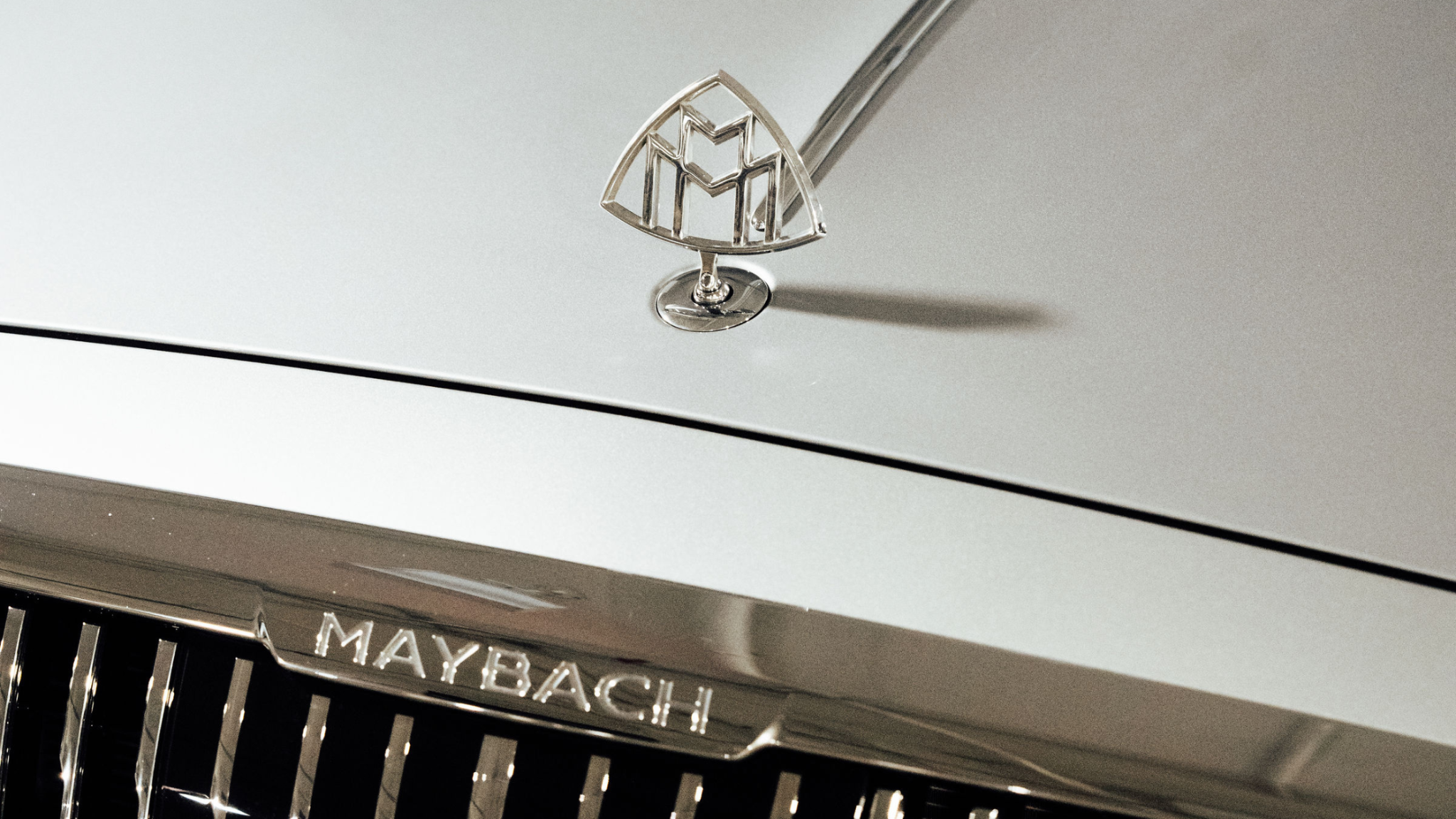 Close up of a Maybach hood ornament and front grille, showcasing chrome detailing on a luxury vehicle.