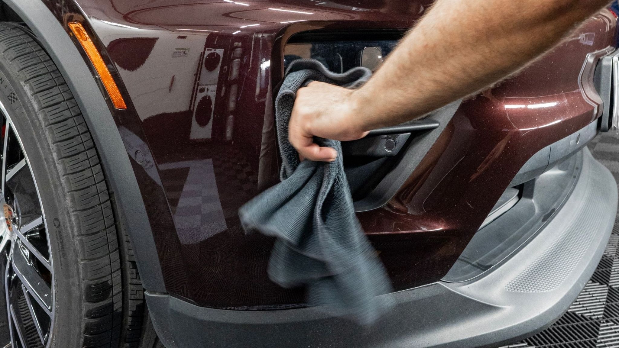 ALPHASHINE detailer hand wiping a luxury vehicle exterior with a microfiber towel during professional car detailing