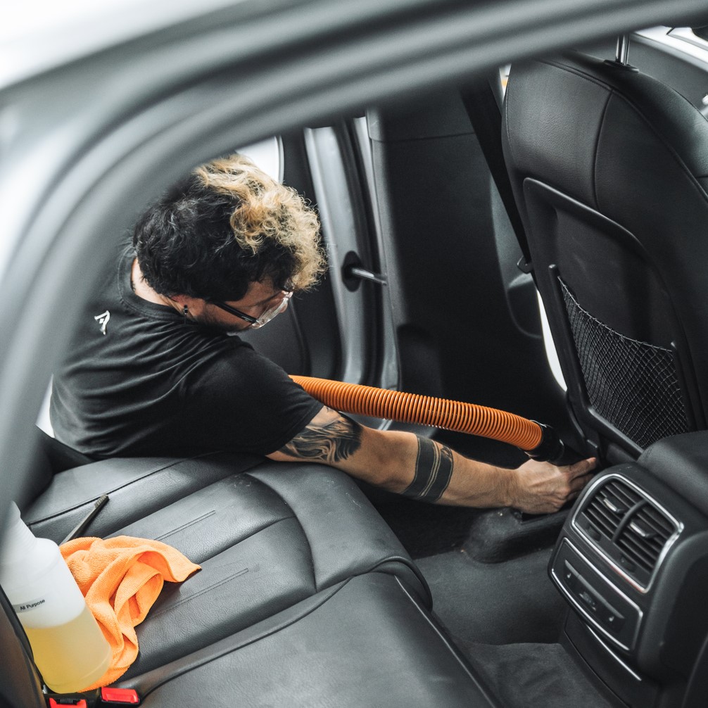 alphashine employee vacuuming interior backseat carpets