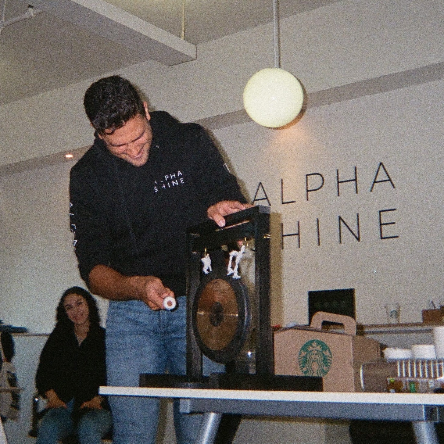 Inclusive team. Image of CEO Martin hitting a gong as Alphashine team celebrates a win.
