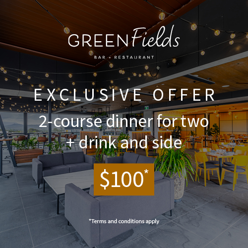 A dining area at a rooftop bar with views of Gold Coast in background