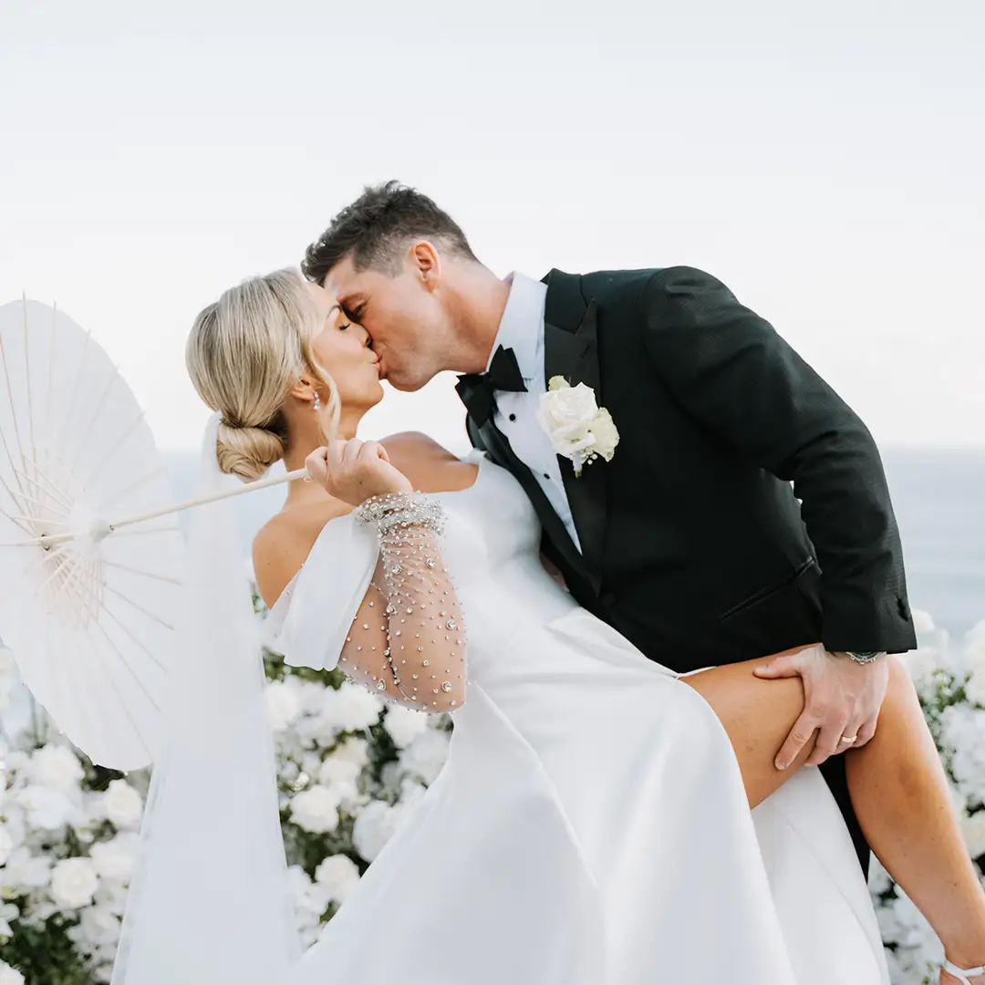 Bride in a stunning designer dress with her veil blowing in the wind.
