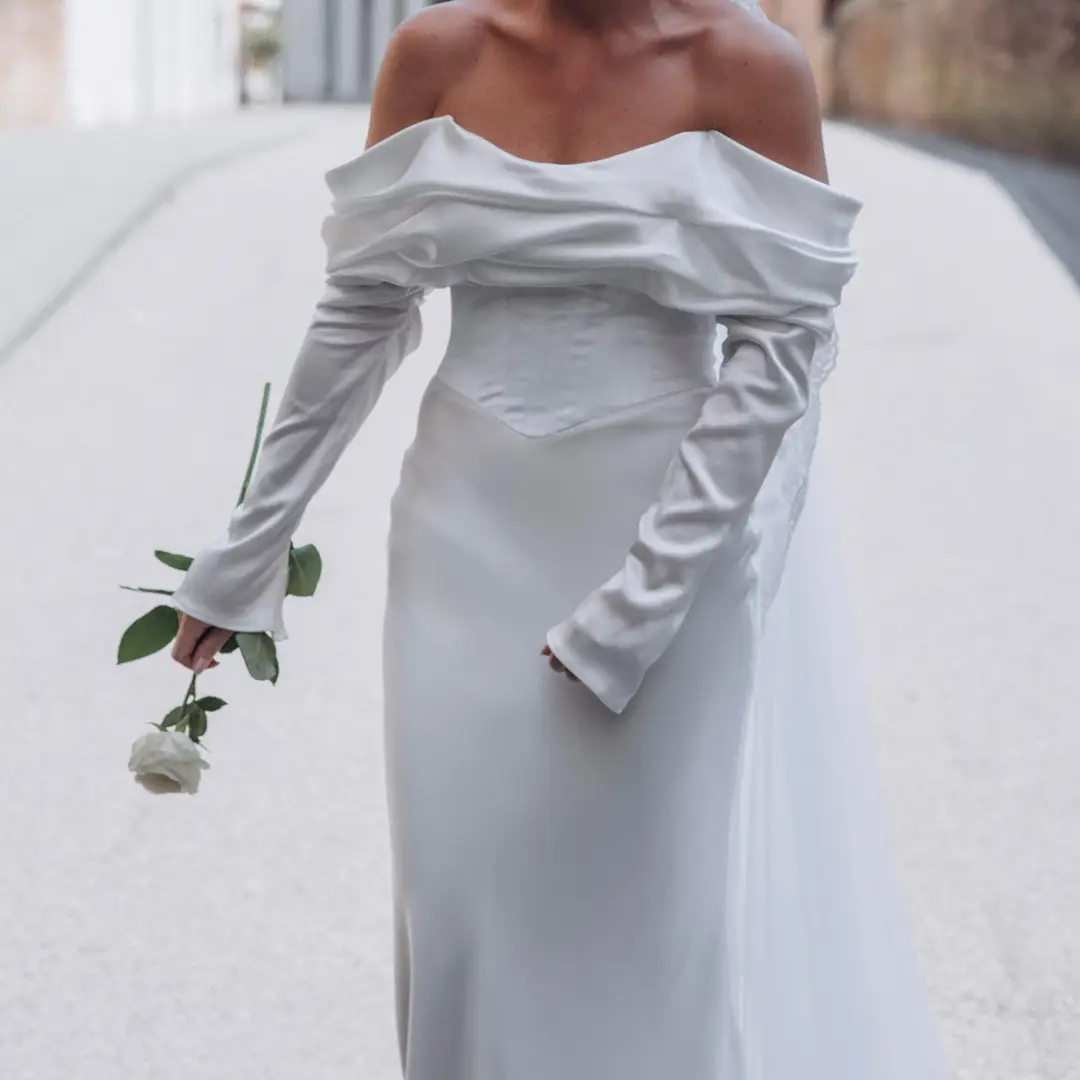Bride in a stunning designer dress with her veil blowing in the wind.