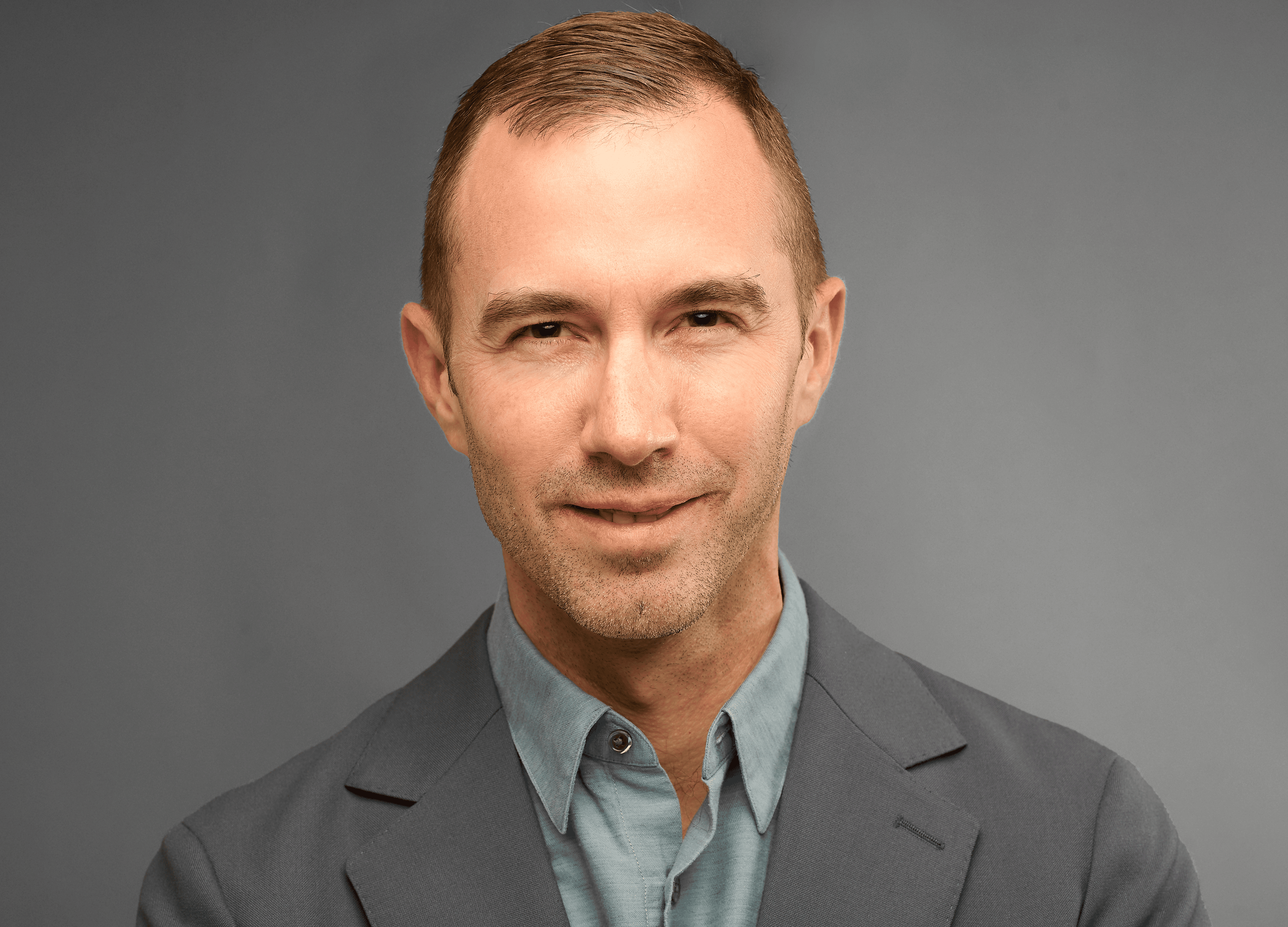 Headshot of Zachariah Hennessey wearing a suit on a gray background