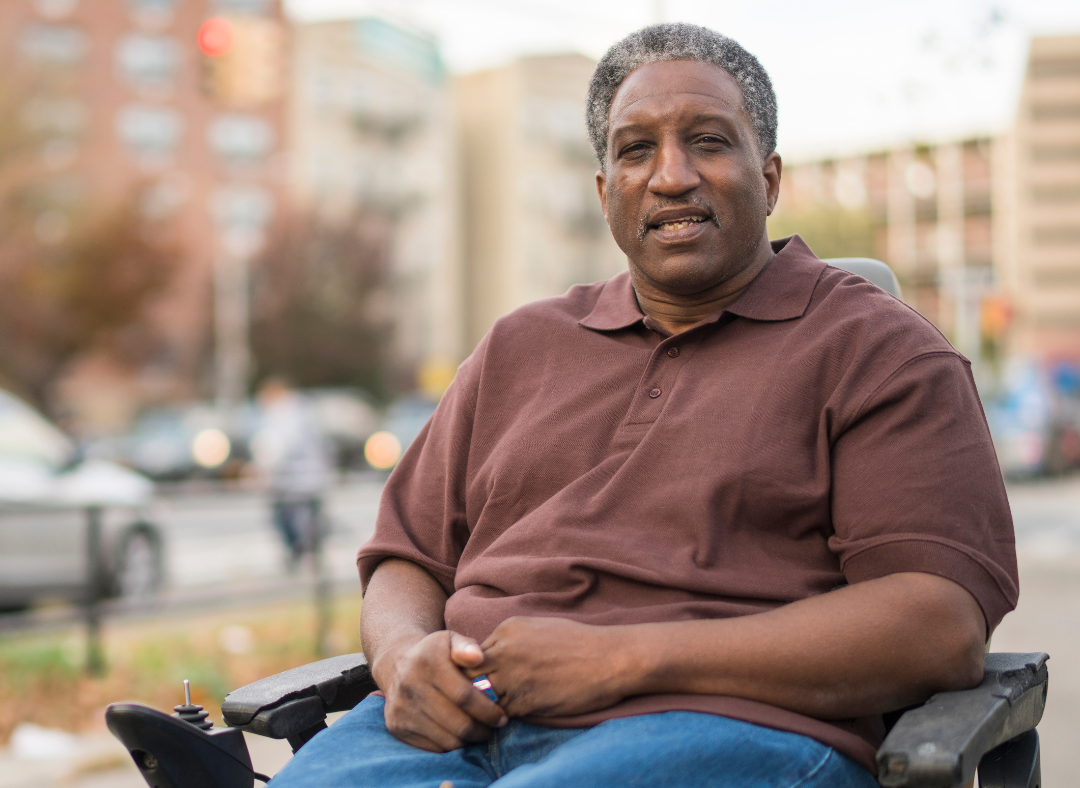 Black man sitting in wheelchair in front of buildings