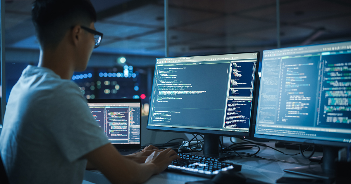 Man on a computer with code on the screen