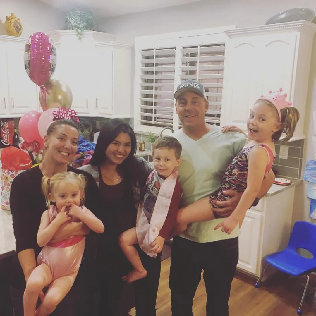 Parents with three children and au pair smiling in a kitchen decorated with birthday balloons.