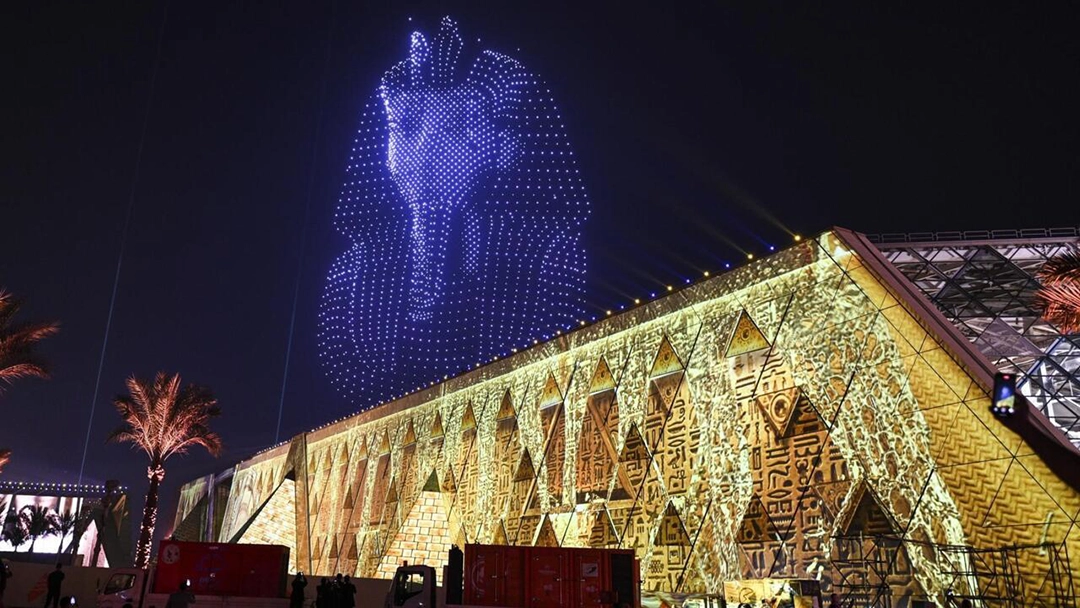 Night view of the Grand Egyptian Museum with hieroglyphic projections and a drone-formed image of Tutankhamun’s mask. Photo: IMG.